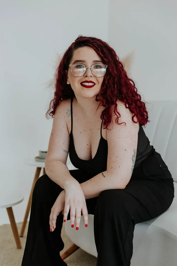 Rhavena Magna, Doula em Goiânia e Consultora de Amamentação, sorrindo sentada no sofá
